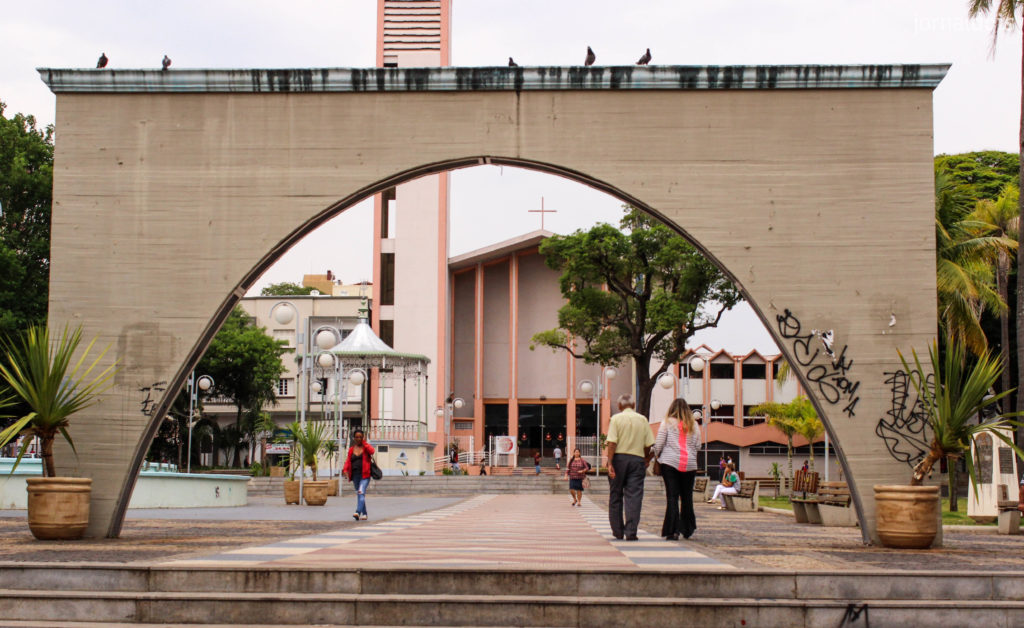 Praça Rui Barbosa, em Bauru, com a Igreja ao fundo e algumas pessoas transitando pela praça.